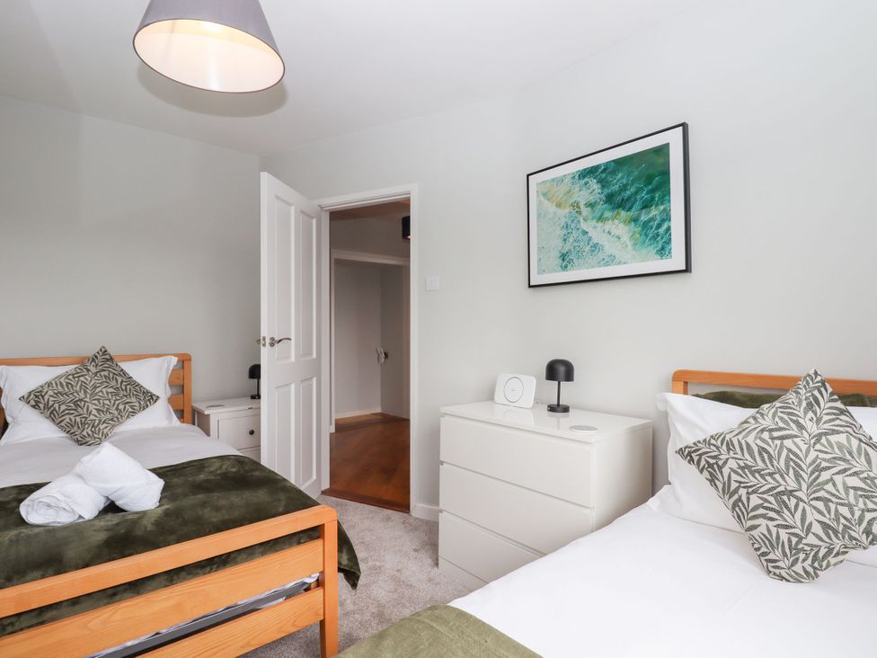 A bedroom with two beds and a bedside table at 15 Summerland Avenue in Dawlish