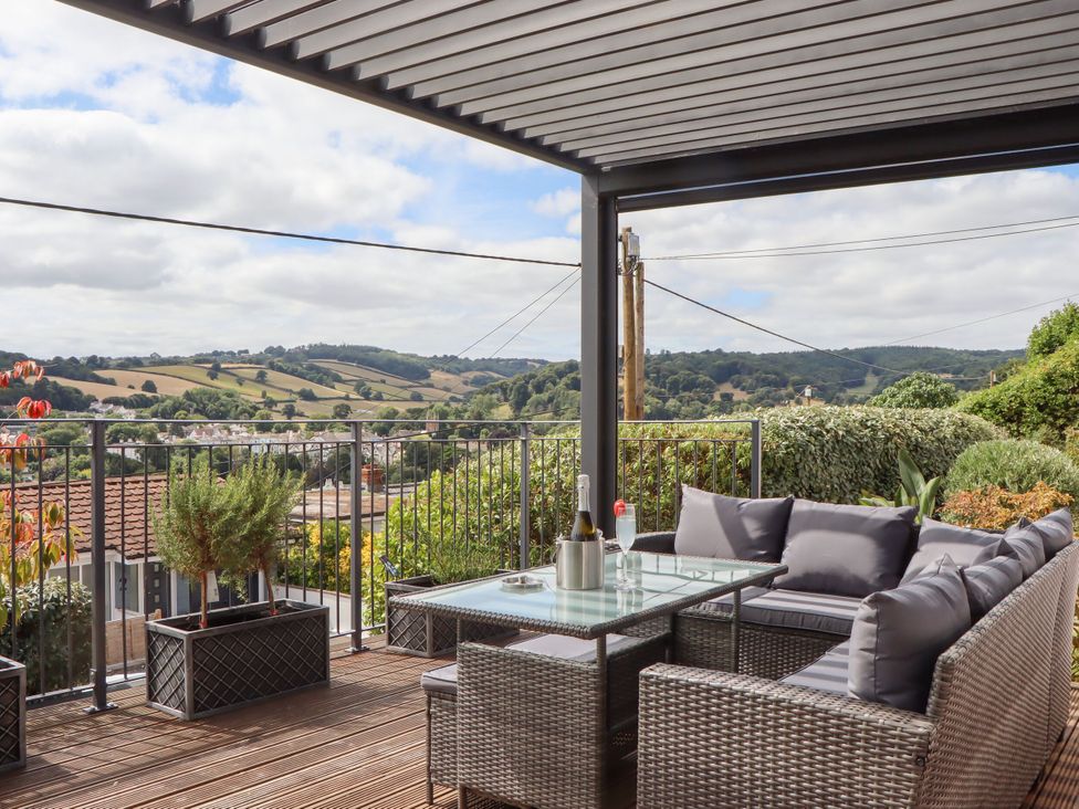 An outdoor space with seating and a table overlooking a landscape at 15 Summerland Avenue Dawlish