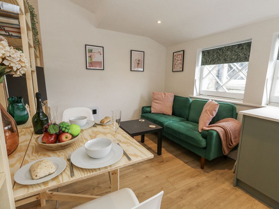 A living room with a sofa and dining table at Sea Pink Studio in Swanage