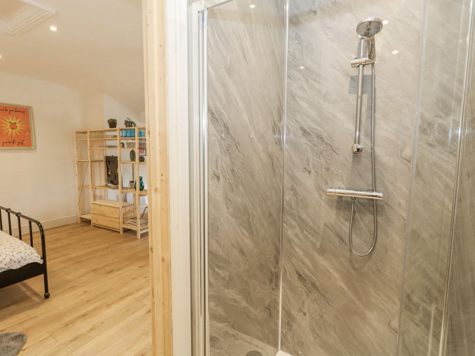 A bathroom with a shower and bed at Sea Pink Studio in Swanage