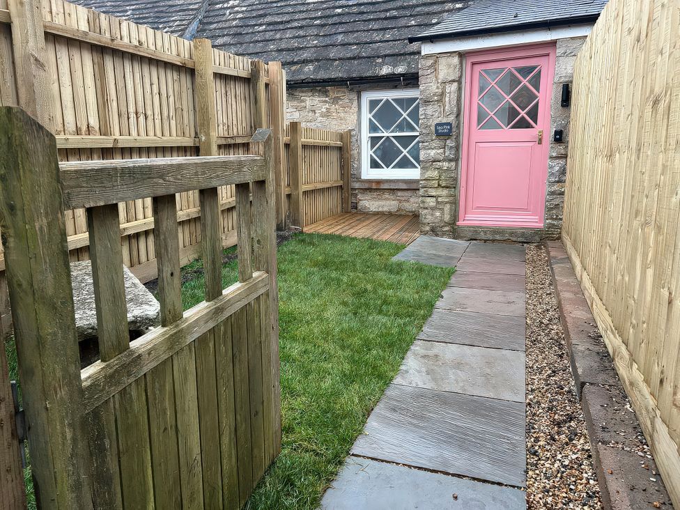 A garden path with a wooden gate and pink door at Sea Pink Studio in Langton Matravers