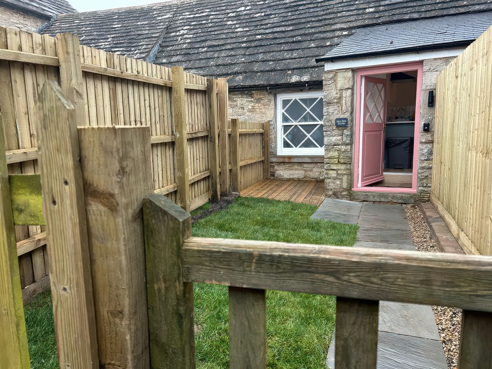 A garden with a wooden fence and a door at Sea Pink Studio in Langton Matravers