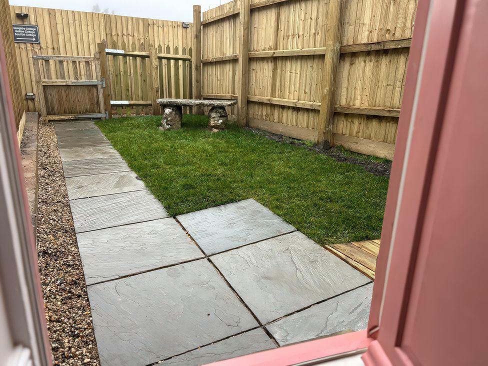 A garden with slate paving and a bench at Sea Pink Studio in Langton Matravers