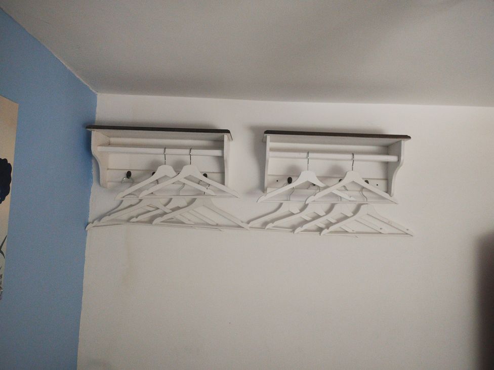 A bedroom with wall-mounted shelves and coat hangers at Llety Beddgelert