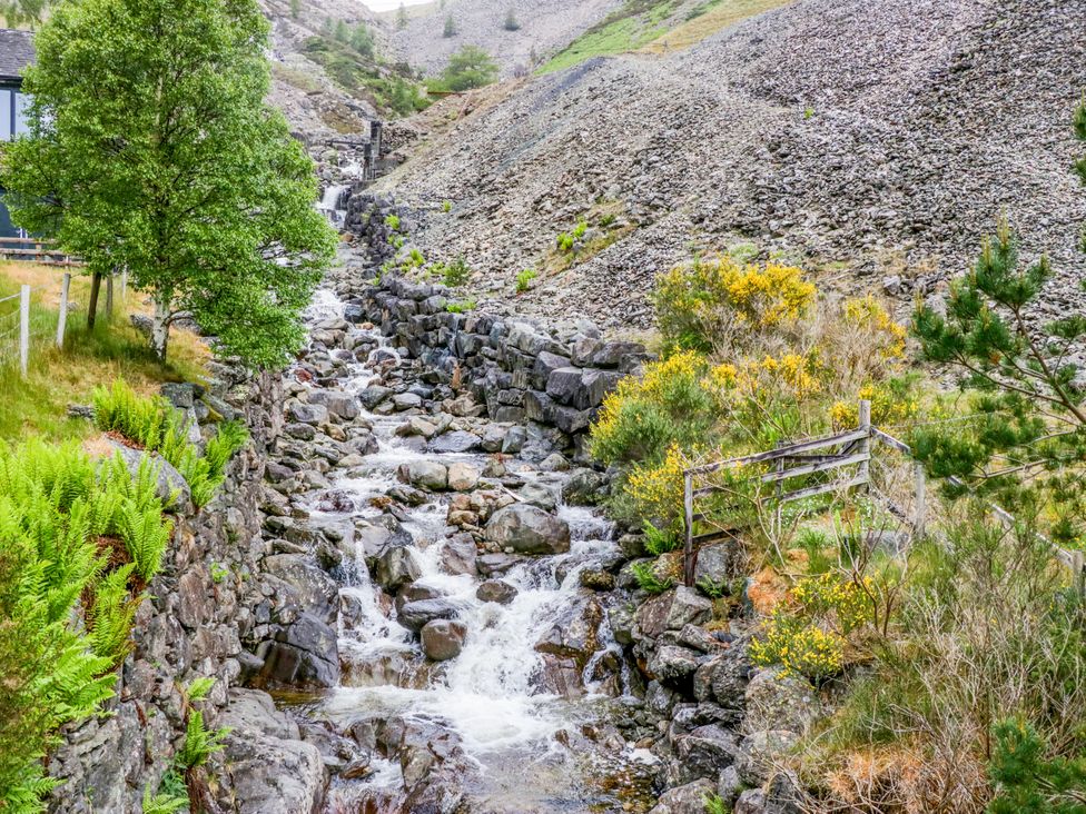A stream flowing through rocks and vegetation at Swirral Edge Cottage in Glenridding