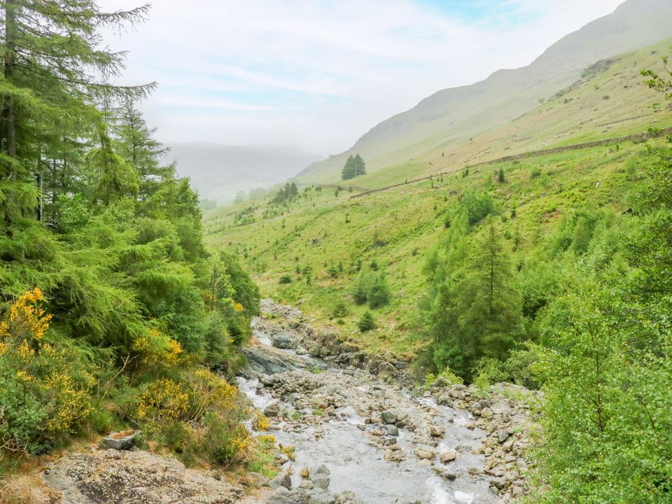 A river flowing through a valley surrounded by trees and hills at Swirral Edge Cottage Glenridding