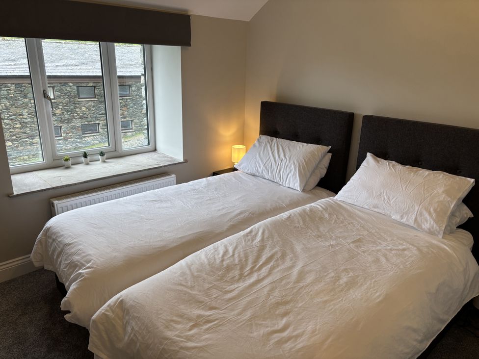 A bedroom with two beds and a window at Swirral Edge Cottage in Glenridding
