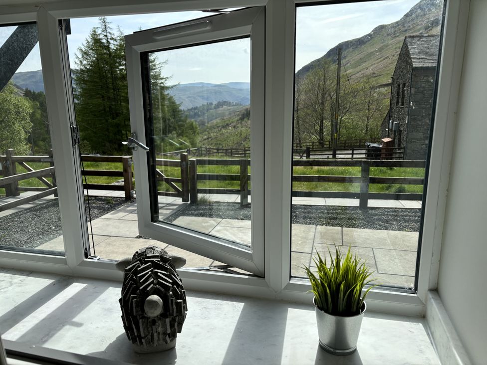 A window with a plant and a sculpture at Swirral Edge Cottage in Glenridding