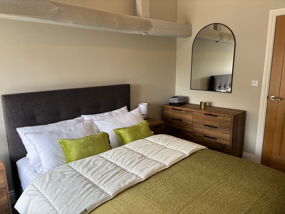 A bedroom with a bed and mirror at Swirral Edge Cottage Glenridding