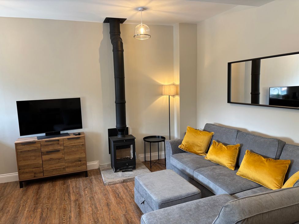 A living room featuring a sofa, television, and fireplace at Swirral Edge Cottage in Glenridding