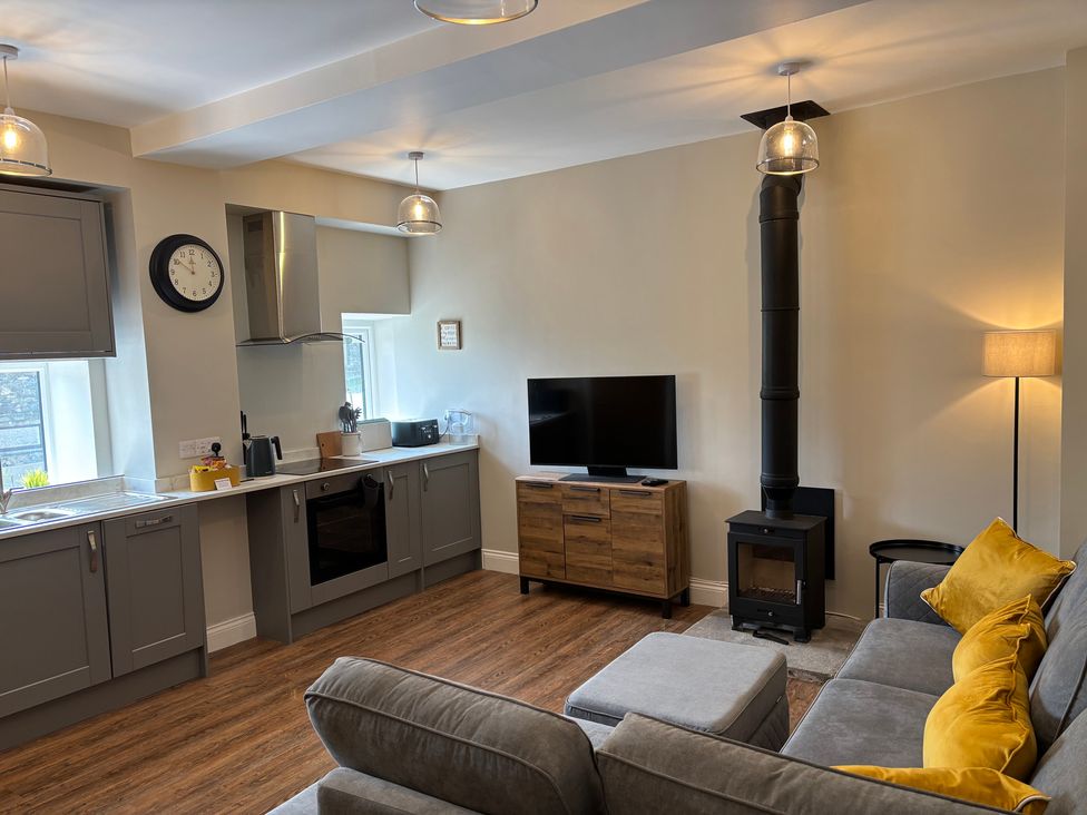 A living room with a stove and television at Swirral Edge Cottage in Glenridding