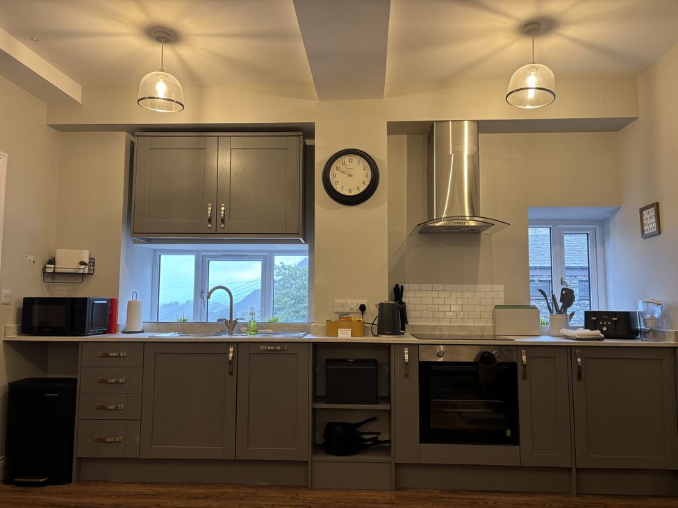 A kitchen with cabinets, oven, and window at Swirral Edge Cottage in Glenridding