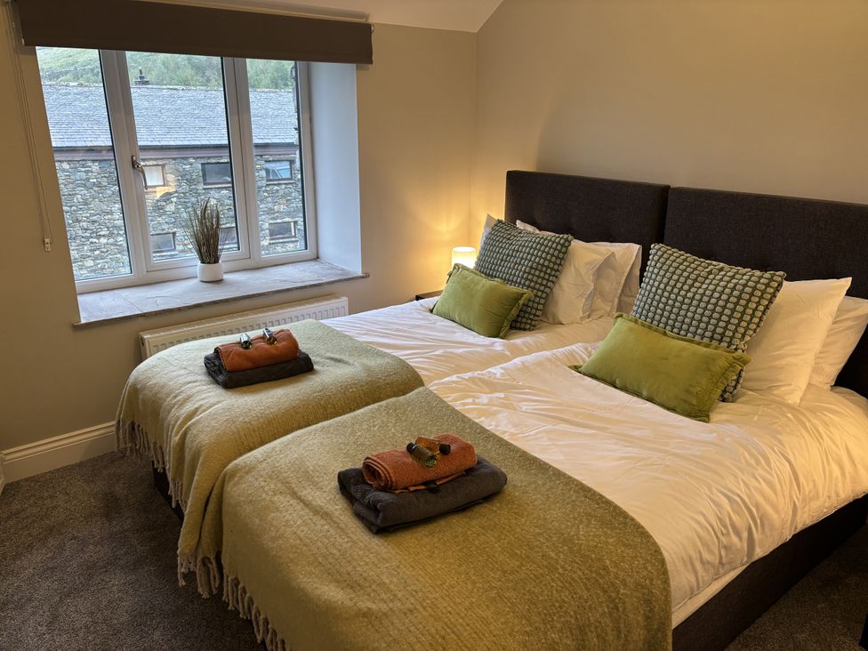 A bedroom with two beds and a window at Swirral Edge Cottage in Glenridding