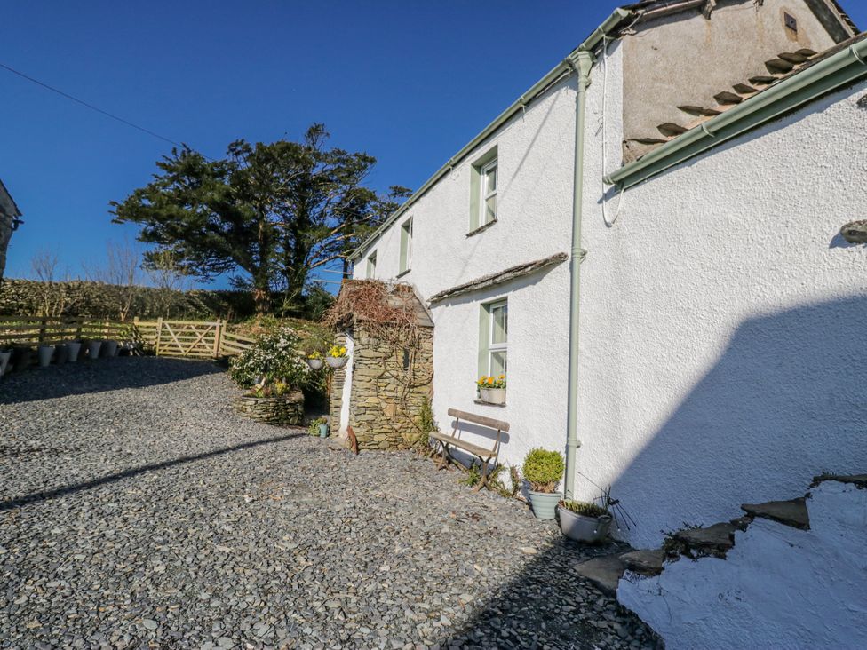 An outdoor view of a house with a bench and flowers at High Ickenthwaite Farmhouse in Ulverston