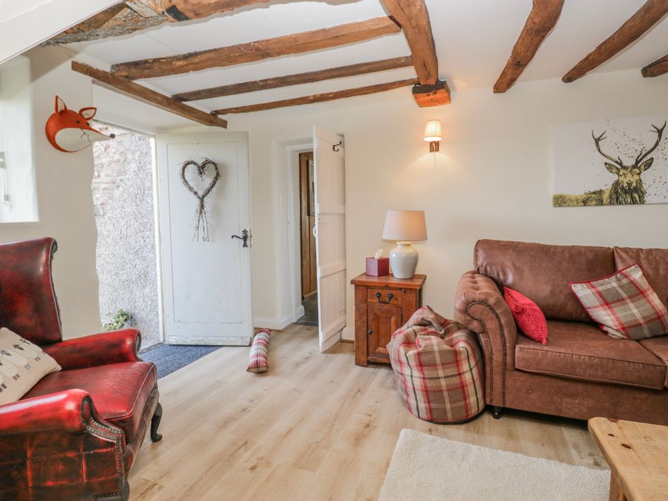 A living room with armchair, sofa, and wooden table at High Ickenthwaite Farmhouse in Ulverston
