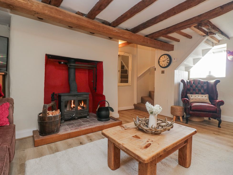 A living room with a fireplace and armchair at High Ickenthwaite Farmhouse Ulverston
