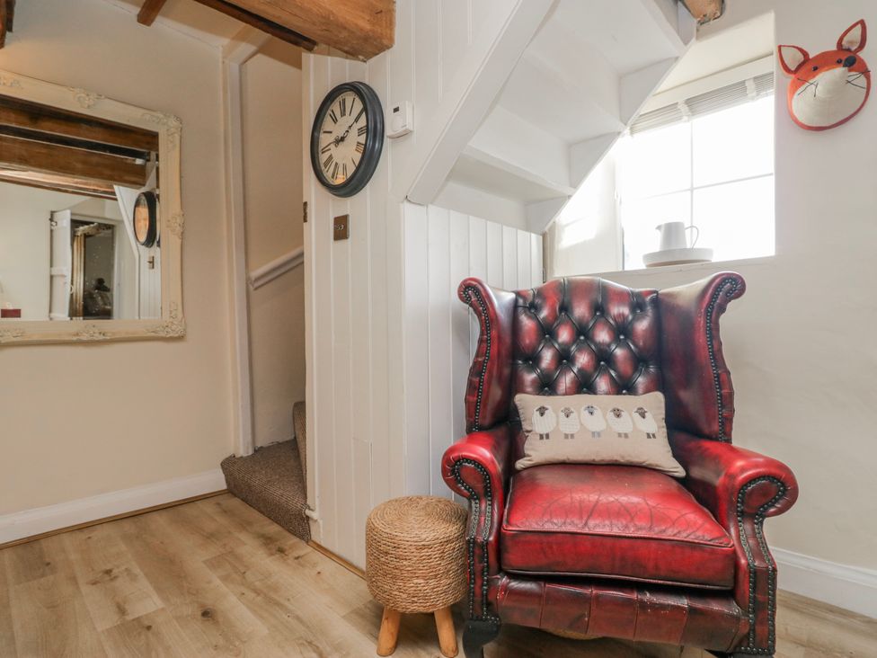 A living room with a red armchair and a mirror at High Ickenthwaite Farmhouse in Ulverston