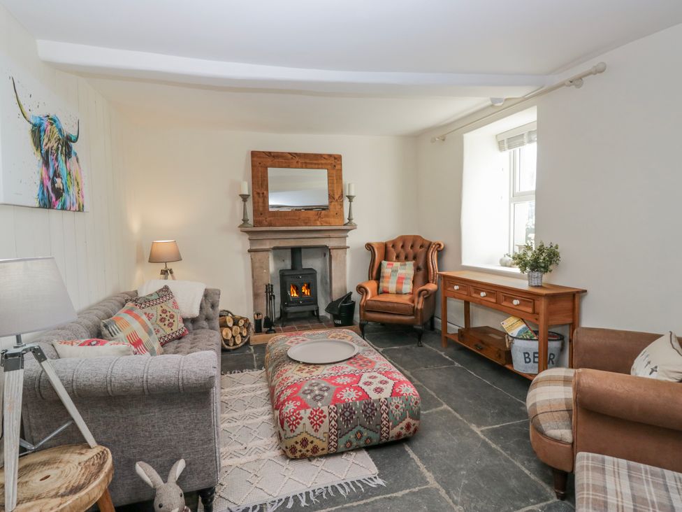 A living room with a fireplace and seating at High Ickenthwaite Farmhouse in Ulverston