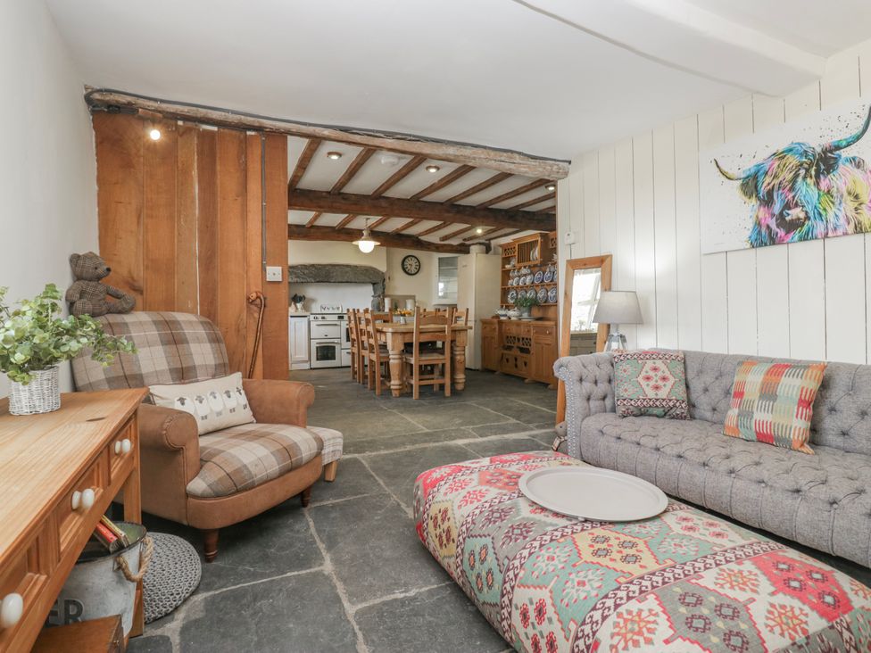 A living room with a sofa and dining area at High Ickenthwaite Farmhouse in Ulverston