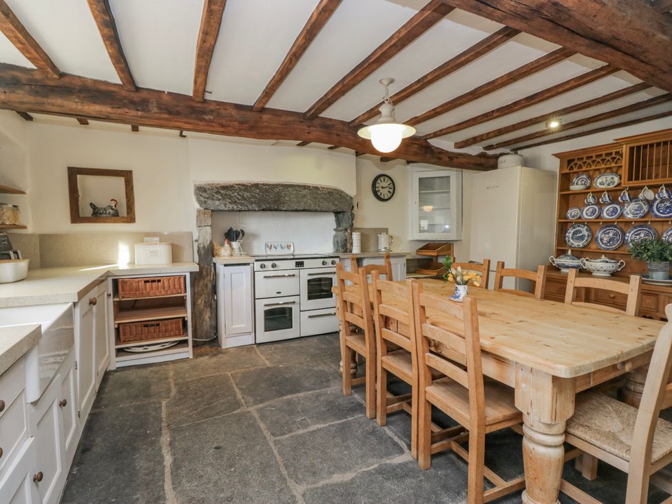 A kitchen with a dining table, oven, and shelves at High Ickenthwaite Farmhouse in Ulverston