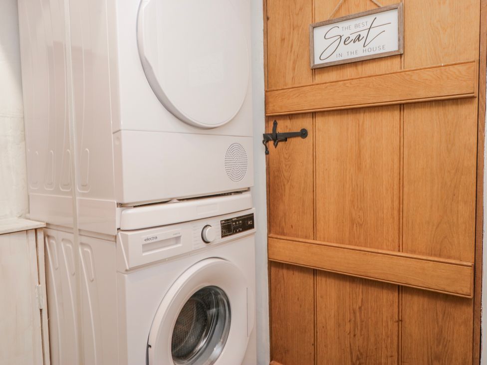 A laundry room with a washing machine and tumble dryer at High Ickenthwaite Farmhouse in Ulverston