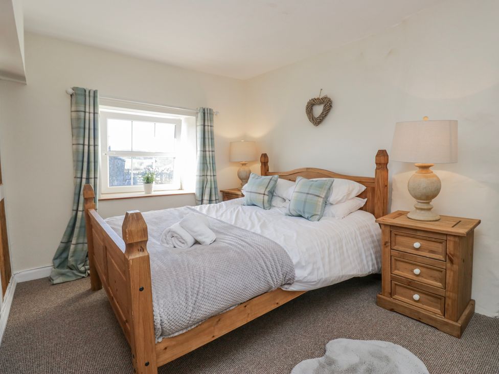 A bedroom with a bed and nightstand at High Ickenthwaite Farmhouse in Ulverston