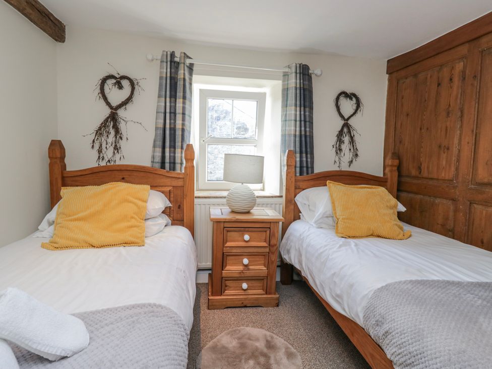 A bedroom with two beds and a window at High Ickenthwaite Farmhouse in Ulverston