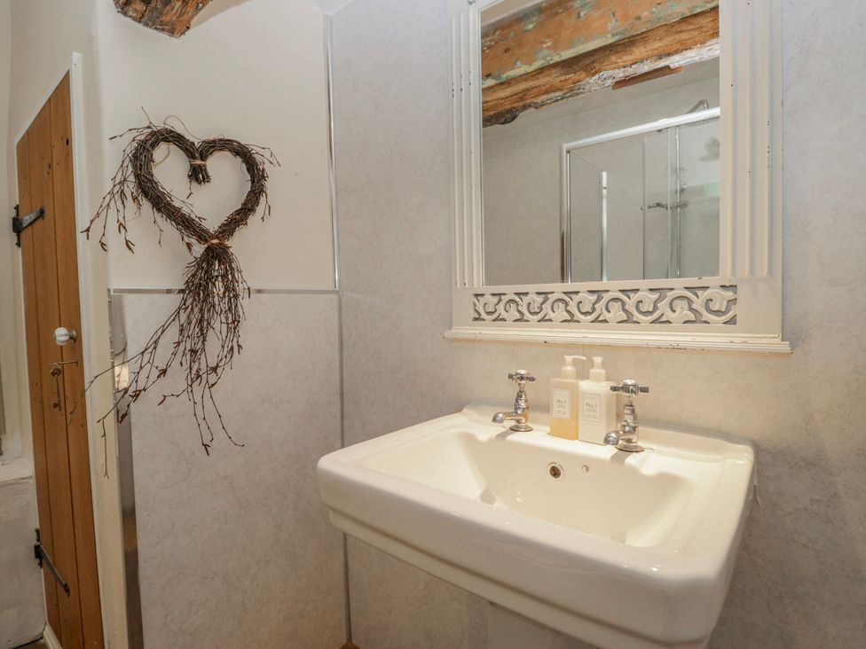 A sink with a mirror and toiletries at High Ickenthwaite Farmhouse Ulverston