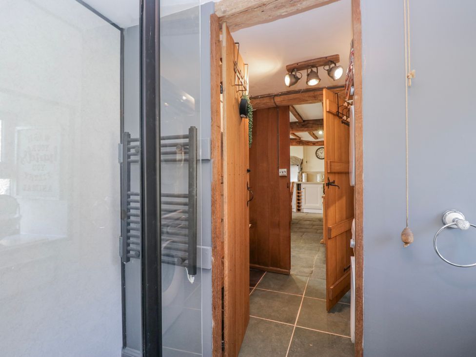 A bathroom with a shower and wooden door at High Ickenthwaite Farmhouse Ulverston