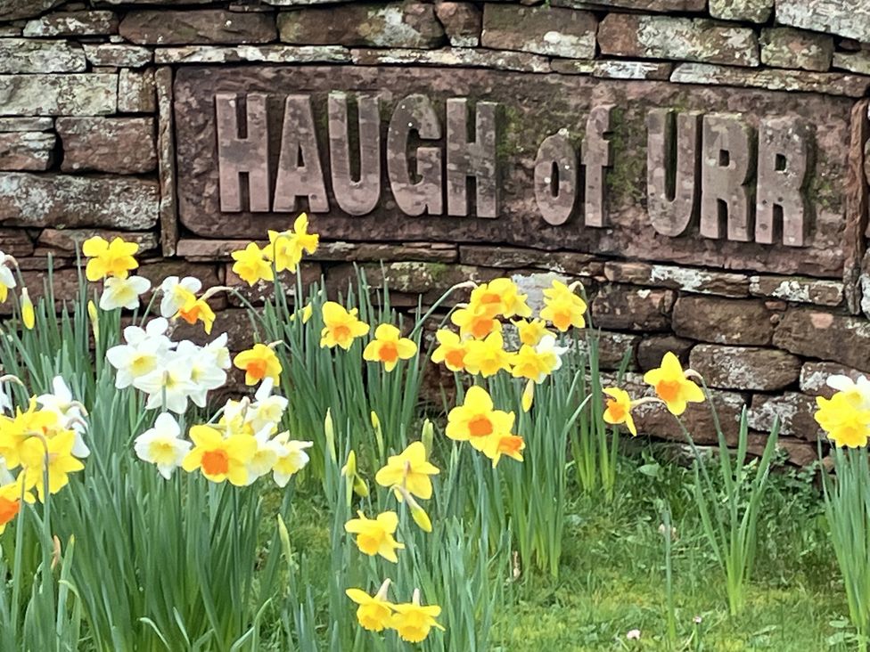 A sign reading Haugh of Urr with flowers in front at The Steading in Castle Douglas