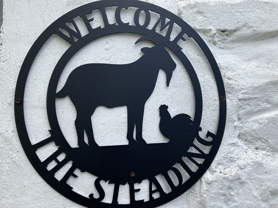 A welcome sign featuring a goat and a chicken at The Steading in Castle Douglas