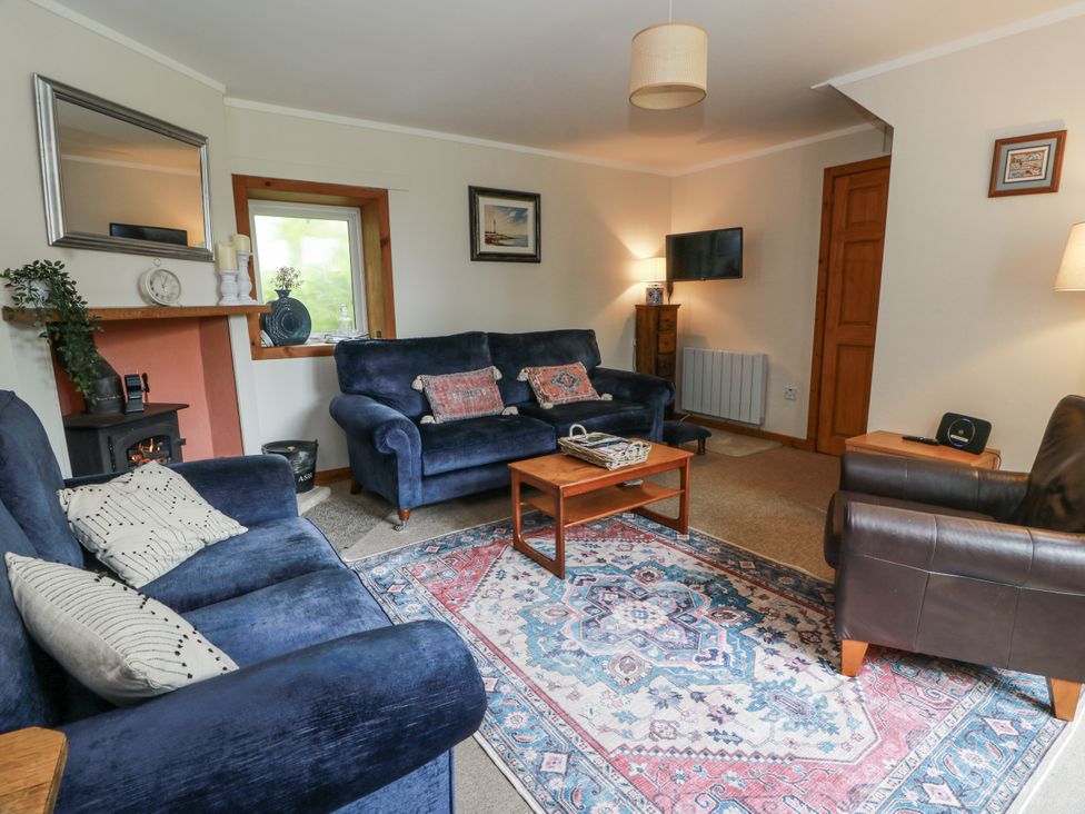 A living room with a sofa, coffee table, and television at The Steading in Castle Douglas