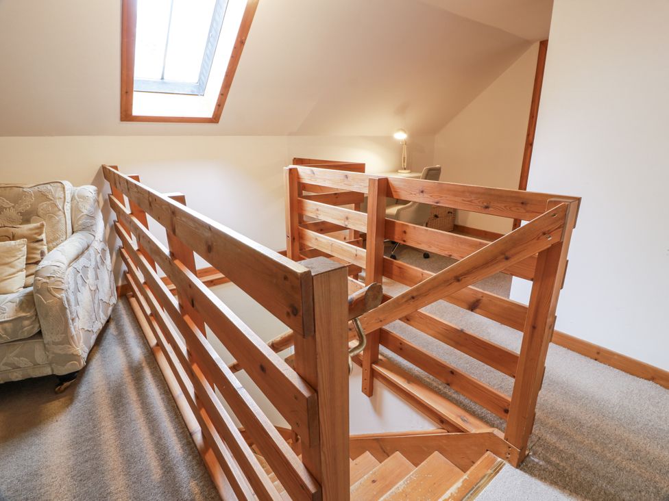 A landing area with a balustrade and sofa at The Steading in Castle Douglas