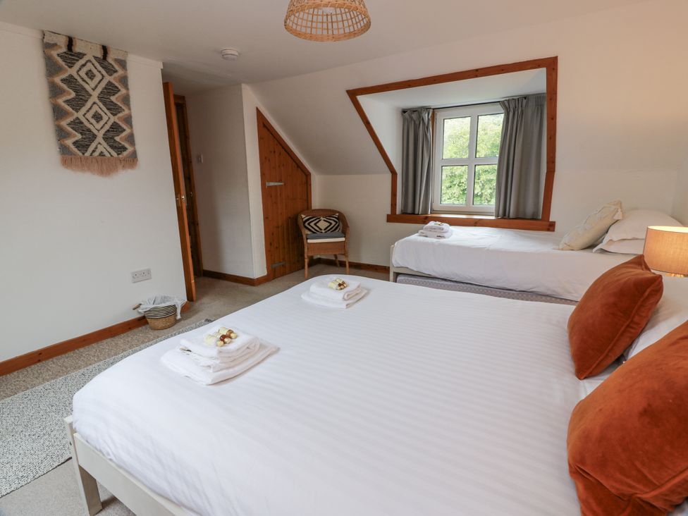 A bedroom with two beds and a window at The Steading in Castle Douglas