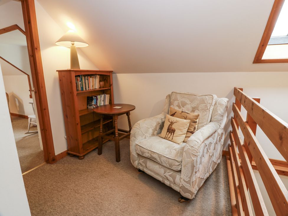 A landing with an armchair and bookshelves at The Steading in Castle Douglas