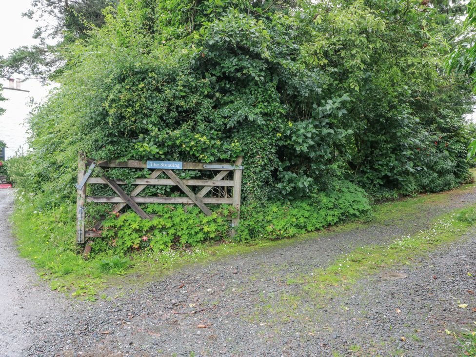 A gate and pathway surrounded by vegetation at The Steading in Castle Douglas