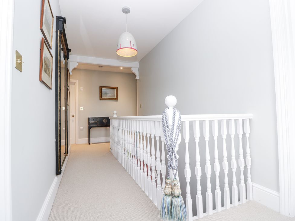 A hallway with a staircase and paintings on the wall at Milston in Chale
