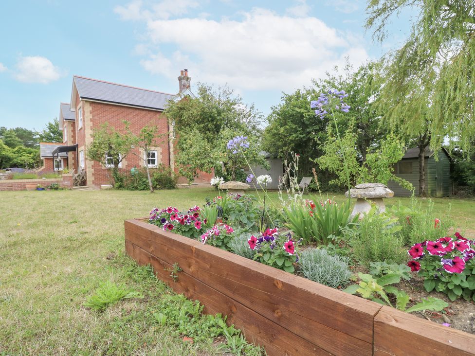 A garden with a flower bed and a house at Milston in Chale