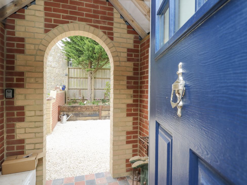An entryway with a blue door and archway leading to a garden at Milston in Chale