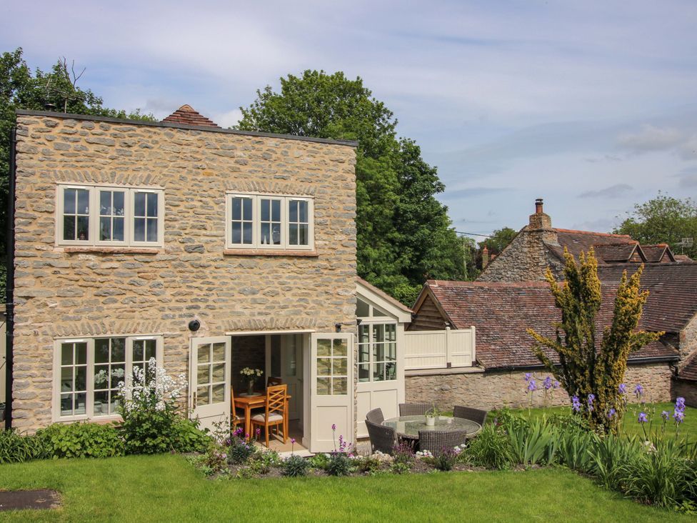 A stone building with patio seating and a garden at 5 Shrewsbury Road in Much Wenlock