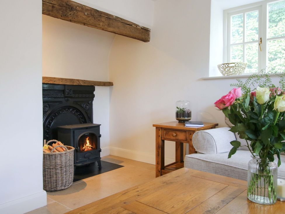 A living room with a fireplace and flowers on a table at 5 Shrewsbury Road in Much Wenlock
