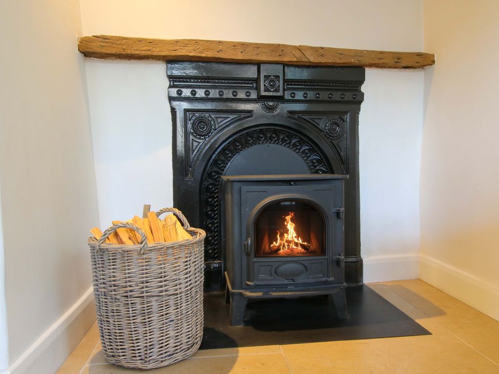 A living room with a wood stove and wood basket at 5 Shrewsbury Road Much Wenlock