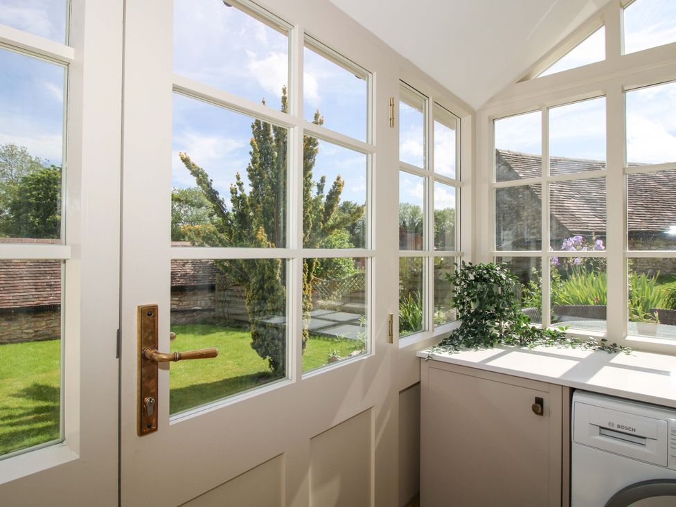 A conservatory with a door and windows overlooking a garden at 5 Shrewsbury Road Much Wenlock