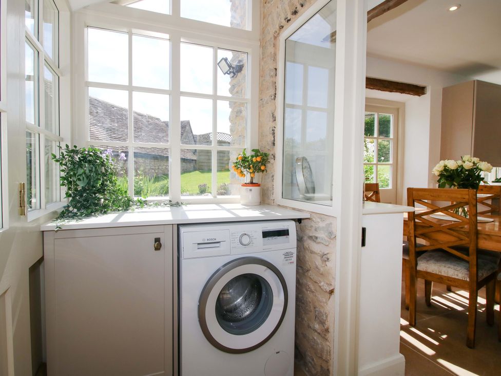A kitchen with a washing machine and dining area at 5 Shrewsbury Road Much Wenlock