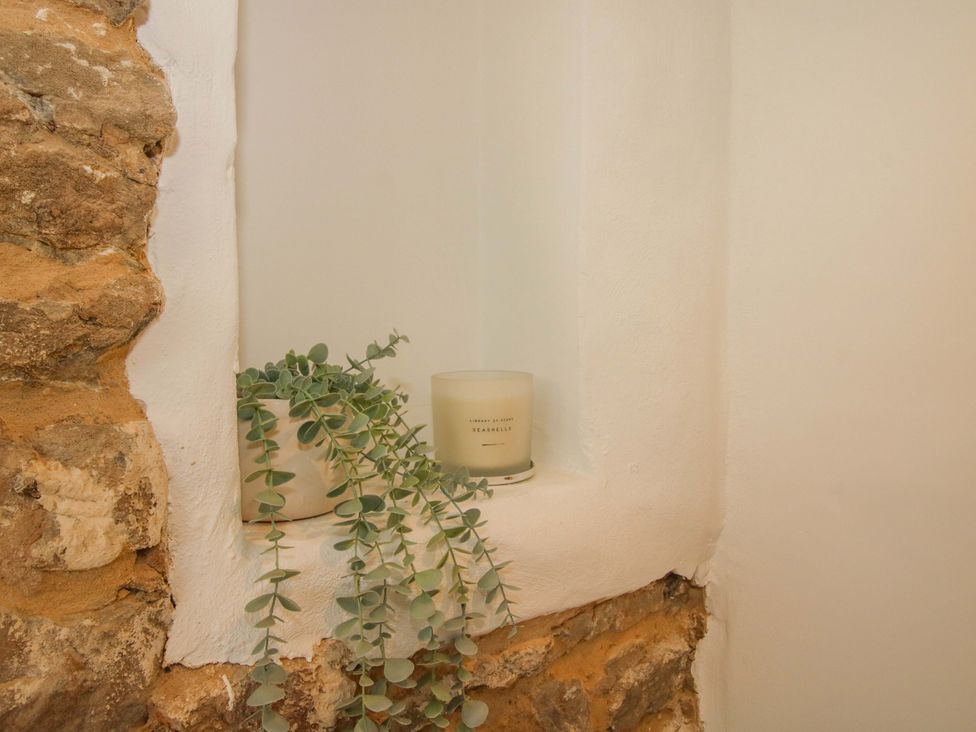 A candle and a plant on a ledge in a wall at 5 Shrewsbury Road, Much Wenlock