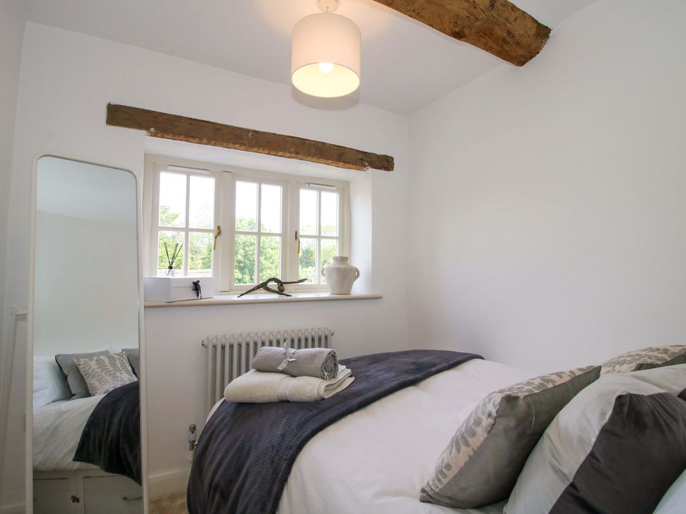 A bedroom with a bed and a mirror at 5 Shrewsbury Road Much Wenlock