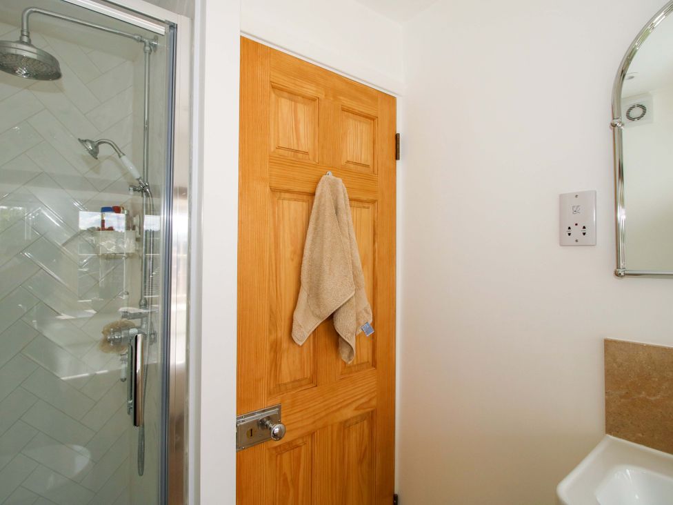 A bathroom with a shower and towel hanging on the door at 5 Shrewsbury Road Much Wenlock