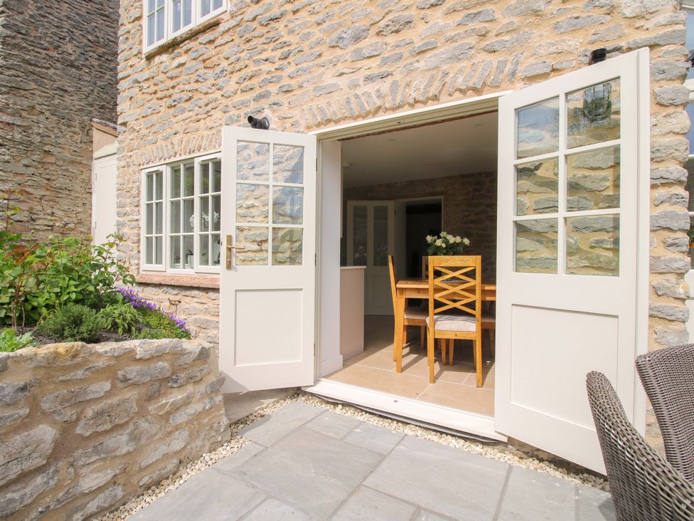 A dining room with a table and chairs leading to a patio at 5 Shrewsbury Road Much Wenlock