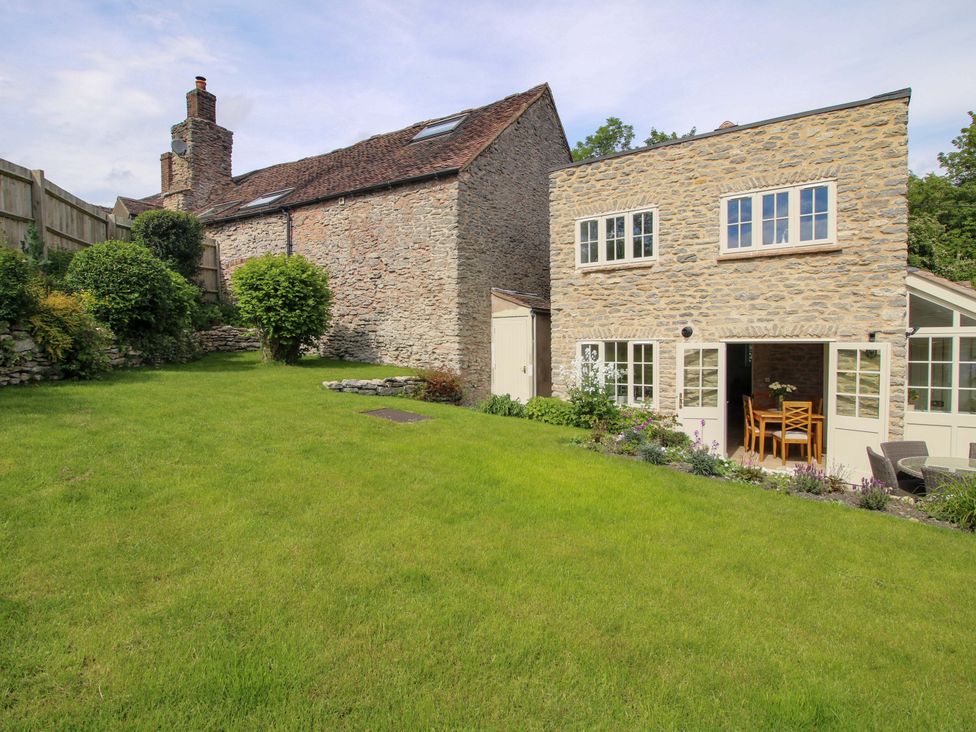 A garden with a stone house and seating area at 5 Shrewsbury Road Much Wenlock