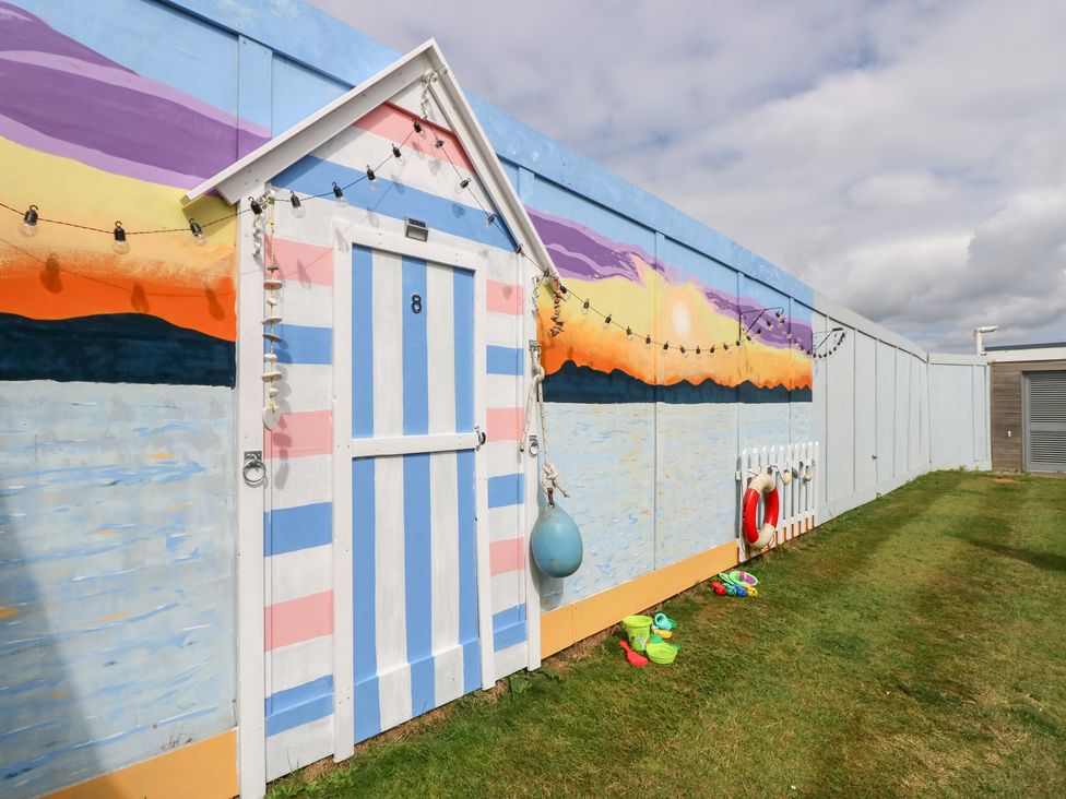 A beach hut with a mural and toys in an outdoor area at Plimoth N8 in Yarmouth
